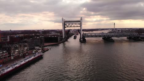 Vista-Aérea-Del-Carguero-Alphenaar-Acercándose-Al-Puente-Ferroviario-Spoorbrug-Elevado-En-Segundo-Plano