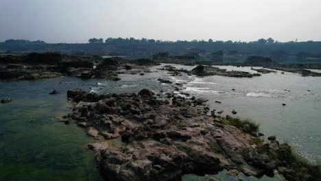 Aerial-forwarding-shot-over-beautiful-Narmada-river-in-Gujrat,-India-surrounded-tropical-green-forest-in-the-background-on-a-bright-sunny-day