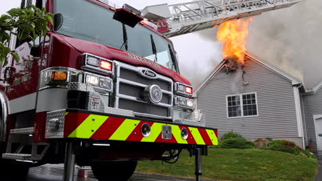 Close-Up-of-the-Front-of-a-Fire-Truck-Parked-Outside-of-an-Intense-House-Fire