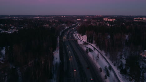 Highway-traffic-and-rural-snowy-area-in-Finland,-rising-forward-aerial