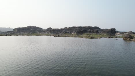 Vadodara-,-Gujarat-,-India---:-Aerial-forwarding-shot-over-Narmada-river-water-flowing-through-rocky-terrain-in-Vadodara-region,-Gujrat,-India-at-bright-sunny-daytime