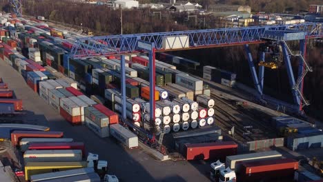 Shipping-container-crane-lift-unloading-heavy-cargo-export-crate-containers-in-shipyard-aerial-view-zoom-in