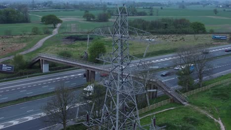 Acelerar-El-Tráfico-Pasando-Por-La-Torre-De-Electricidad-De-Pilón-En-La-Autopista-M62-Vista-Aérea-Cerca-De-La-órbita-Izquierda