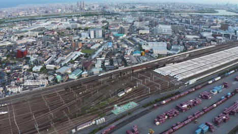 Vista-Aérea-Mientras-El-Tren-Bala-Shinkansen-Pasa-Por-La-Estación-Y-El-Depósito-De-Carga