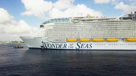 Drone-shot-of-the-Wonder-Of-The-Seas-Royal-Caribbean-cruise-ship-docked,-rotating-around-the-name