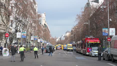 Los-Agentes-De-Policía-Se-Mantienen-Alerta-Mientras-Los-Peatones-Cruzan-La-Calle-Frente-A-Un-área-Acordonada-Durante-Un-Ejercicio-De-Evacuación-De-Emergencia-Médica-Y-Policial-En-Madrid,-España