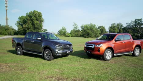 Malaysia,-March-13,-2022:-two-4x4-Isuzu-D-Max-pick-ups-in-dark-orange-color-and-black-on-a-grassy-field