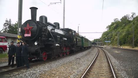 Three-conductors-posing-in-front-of-steam-train-standing-in-station