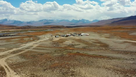Aerial-drone-of-the-high-altitude-alpine-plain-of-Deosai-National-Park-located-between-Skardu-and-Astore-Valley-in-Pakistan-with-a-campground-in-the-distance-on-a-sunny-summer-day