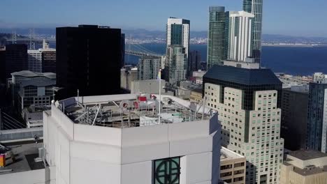 Vista-Aérea-Hacia-Una-Bandera-Del-Arco-Iris-En-La-Parte-Superior-De-Un-Edificio-En-El-Centro-De-San-Francisco,-Ee.uu.---Inclinación,-Disparo-De-Drones