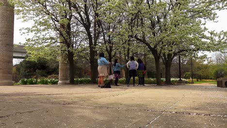 Asian-Family-Taking-Photos-In-City-Park-Under-Blooming-Spring-Trees