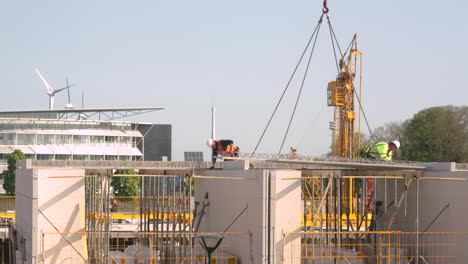 Industrial-scene-of-workers-placing-of-prepared-floor-elements-time-lapse-showing-half-build-houses-with-construction-part-of-next-phase-and-storey-with-large-crane-handing-over-the-material