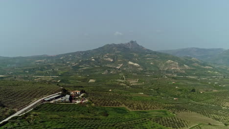 Aerial-flyover-italian-plantation-fields-with-mountain-landscape-in-background-during-foggy-day-on-Sicily-Island