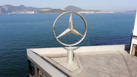 Mercedes-Benz-sign-spinning-on-top-of-Hong-Kong-Mercedes-Benz-main-showroom,-Aerial-view