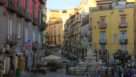 Nápoles,-Italia:-Vista-De-Una-Famosa-Fuente-En-La-Plaza-Monteoliveto-En-El-Centro-Histórico-De-Nápoles,-Italia-Puesta-De-Sol-Con-Turistas-Dando-Vueltas