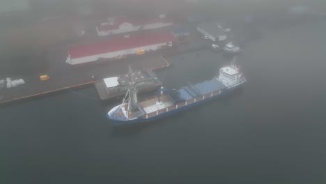 Entladen-Von-Fischaktivitäten-Von-Einem-Frachtschiff-Während-Niedriger-Wolken-In-Faskrudsfjordur,-Ostisland