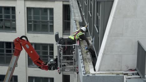 Bauarbeiter-In-Hubarbeitsbühnen,-Die-Fliesen-An-Der-Außenseite-Eines-Neuen-Apartmentgebäudes-Im-Zentrum-Von-London-Befestigen