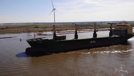 Lufthafen-Seitenansicht-Des-Frachtschiffs-Aal-Paris,-Das-An-Einem-Sonnigen-Tag-Entlang-Der-Oude-Maas-Mit-Stiller-Windkraftanlage-Im-Hintergrund-Fährt