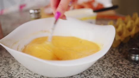 Close-up-of-a-woman-beating-in-slow-motion-organic-eggs-in-bowl-during-daytime