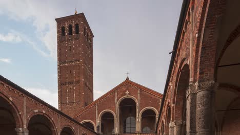 Time-lapse-of-Saint-Ambrogio-church-brick-building-with-bell-towers,-courtyard,-arches-at-overcast-day,-Milan,-Lombardy,-Italy