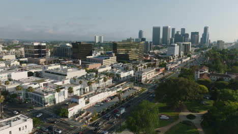 Fliegen-über-Den-Beverly-Hills,-Luftdrohnenaufnahmen-Der-Geschäftigen-Stadt-Mit-Bäumen-Und-Der-Skyline-Der-Stadt-Am-Horizont