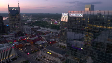 Vista-Aérea-Alrededor-Del-Edificio-Bridgestone,-Con-Vista-A-La-Calle-Broadway,-Anochecer-En-Nashville,-Estados-Unidos---Dando-Vueltas,-Disparo-De-Drones