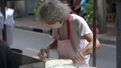 Man-preparing-street-food,-fried-dough-street-stall,-Silom,-Bangkok