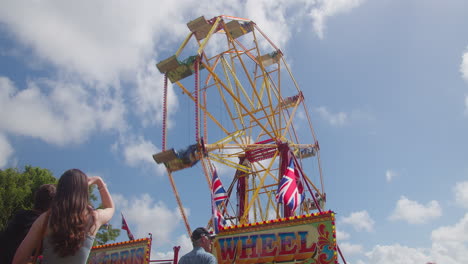 People-Enjoy-Thrill-of-Ferris-Wheel-at-Fairground-for-the-Royal-Cornwall-Show-2022-in-Wadebridge,-Cornwall-static-low-angle-view