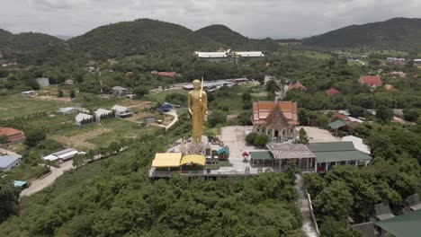 Aerial-orbiting-over-Thai-temple-of-Wat-Khao-Noi-with-His-majestic-Statue-of-Golden-buddha,-Hua-Hin