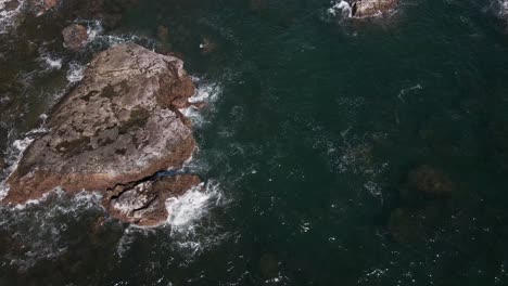 downward-tilted-drone-footage-of-the-Pacific-Ocean-pounding-the-coastal-rocks-on-a-tropical-island