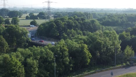 Vehicles-travelling-on-highway-background-aerial-descend-to-5G-broadcasting-tower-antenna-in-British-countryside