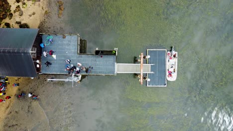Overhead-Shot-Of-People-Standing-On-Patio-Of-Unique-Small-Cottage-Built-On-Water-Sea,-California