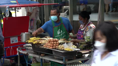 Straßenlebensmittelstand-In-Silom-Bangkok,-Mann-Und-Frau,-Die-Lokales-Straßenessen-Verkaufen