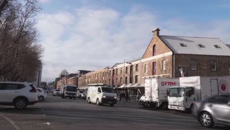 Cars-driving-down-historic-street-at-Salamanca-with-architectural-sandstone-buildings,-Hobart,-Tasmania-on-clear-winter-day-with-blue-sky,-Hobart,-Tasmania,-Australia