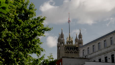 Un-Tiro-Lejano-De-La-Torre-Victoria-Con-Una-Bandera-Union-Jack-Ondeando-En-El-Viento-En-El-Palacio-De-Westminster,-Londres,-Inglaterra