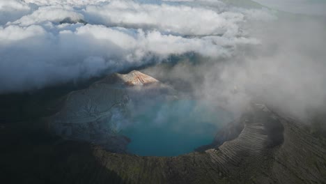 Panoramic-view-of-Ijen-volcano-with-turquoise-sulfur-lake,-clouds-rolling-in-over-mountains