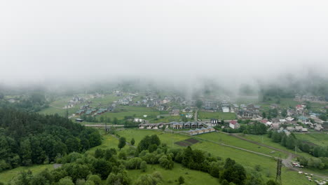 AERIAL---The-town-of-Bakuriani,-Georgia-in-the-fog,-mist,-forward-shot