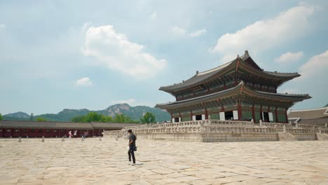Man-tourist-filming-hyper-lapse-video-walking-around-Gyeongbokgung-Palace-on-a-sunny-day