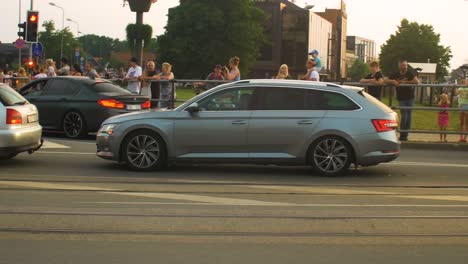 FIA-European-Rally-Trophy-2022-festive-start-and-cars-parade-at-streets-of-Liepaja-,-golden-hour-evening,-rally-cars-passing-spectators,-medium-wide-angle-handheld-tracking-shot