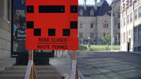 Road-closed-sign-in-downtown-Ottawa-with-the-Parliament-of-Canada-in-the-background-on-a-sunny-summer-day---4K