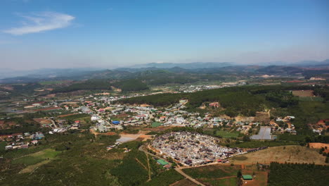 Aerial-drone-shot-over-village-houses-surrounded-by-green-agricultural-fields-in-Tu-Tra,-Don-Duong-District,-Lam-Dong,-Vietnam-on-a-bright-sunny-day