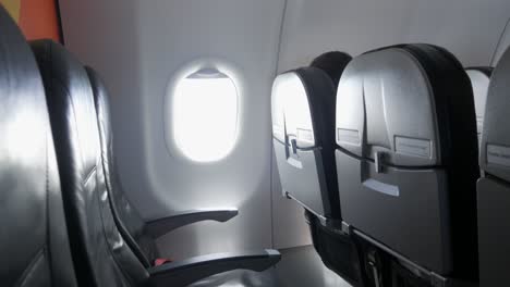 Interior-of-commercial-airplane-empty-cabin-with-black-passenger-seats-in-economy-class-cabin