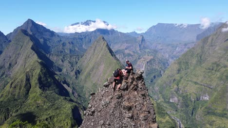 Drone-footage-of-two-people-climing-steep-rock-in-front-a-scenery-of-the-Cirque-of-Mafate-at-the-Reunion-island