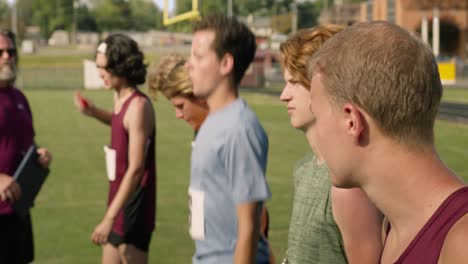 Runners-line-up-for-race-on-a-summer-sunny-day,-runner-looks-at-his-competition