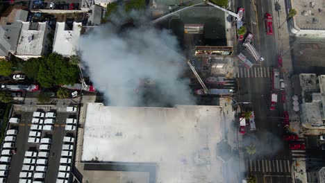 Feuerwehrleute-Löschen-Ein-Brennendes-Und-Rauchendes-Gebäude-In-Einer-Stadt---Luftbild