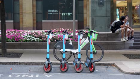 London-Canary-Wharf-Agosto-De-2022-Fila-De-Scooters-Eléctricos-Y-Bicicletas-Estacionados-Al-Lado-De-La-Carretera