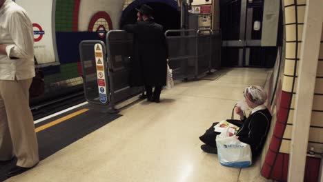 Bond-Street-Train-Station--London,-England---19-July-2022,-Commuter-Fanning-Herself-Below-Ground-In-London-Underground-Station-Platform