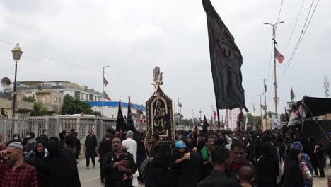 At-the-juloos-or-Muharram-Parade,-also-known-as-Muharram-Ul-Haram,-a-large-number-of-people-are-marching-and-waving-flags-of-different-colors,-but-they-are-all-there-to-grieve