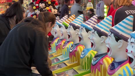 Mother-holding-a-kid-up-to-drop-the-ball-in-laughing-clowns'-mouth,-popular-carnival-games-at-Ekka-Brisbane-Showgrounds,-Royal-Queensland-Show,-Australia