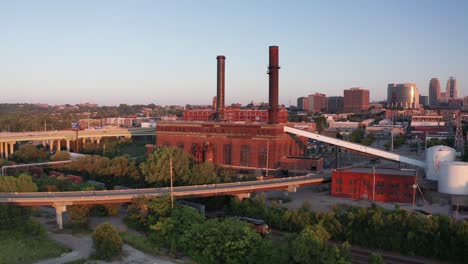 Wide-push-in-aerial-shot-of-a-brick-factory-in-Kansas-City,-Missouri-as-a-freight-train-passes-by-at-sunset